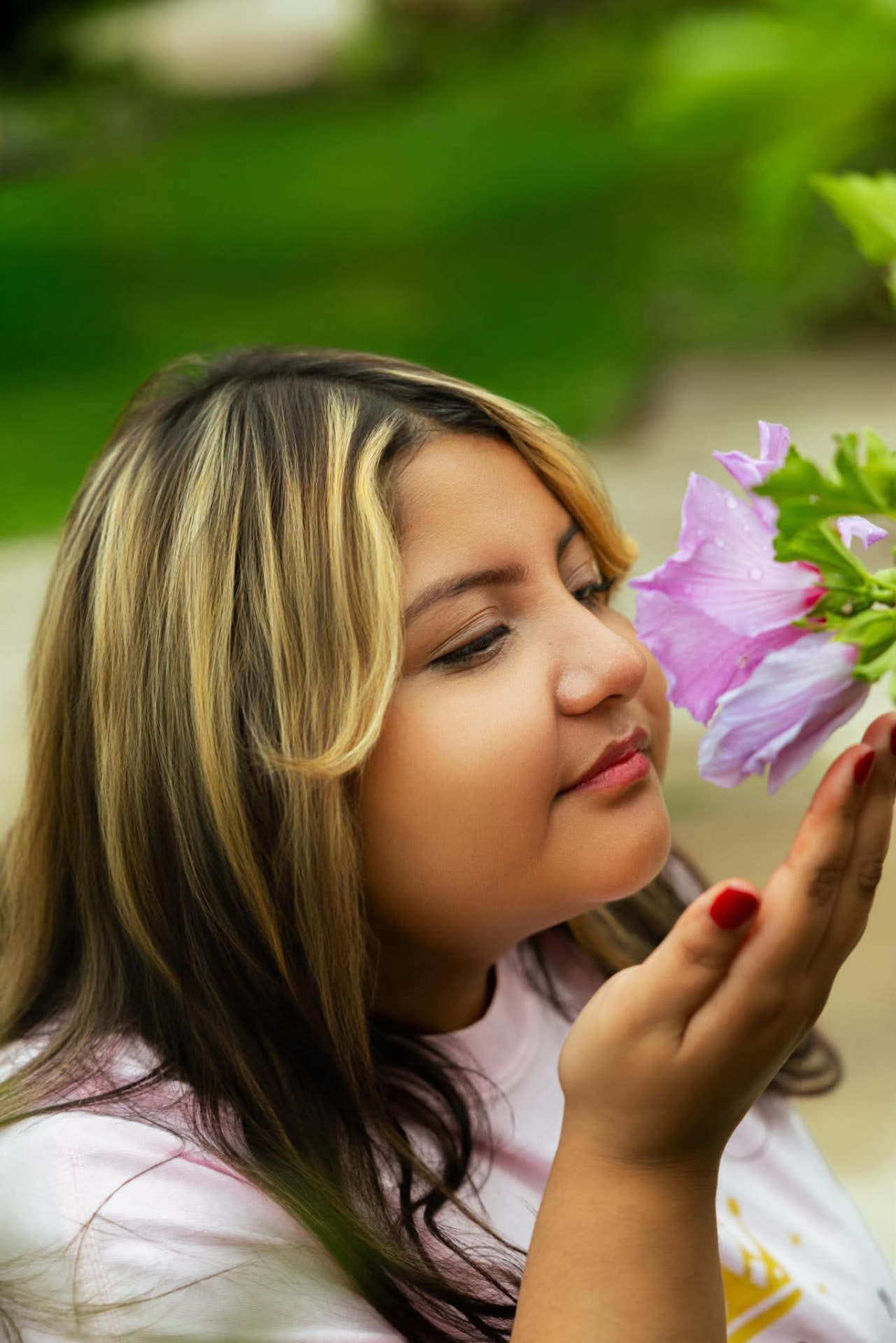 A woman leaning in to smell a blossom in a garden